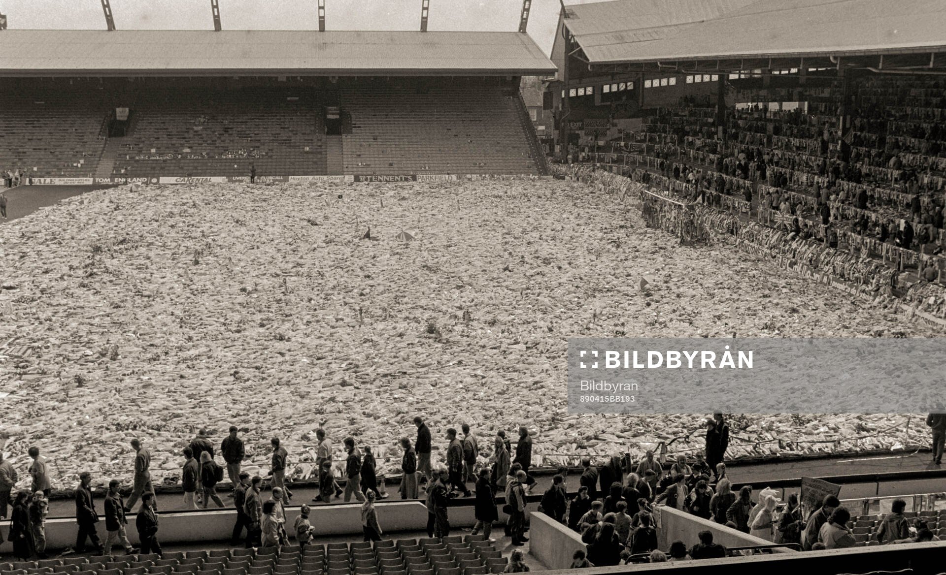 People look at a sea of flowers and scarves at Anfield to