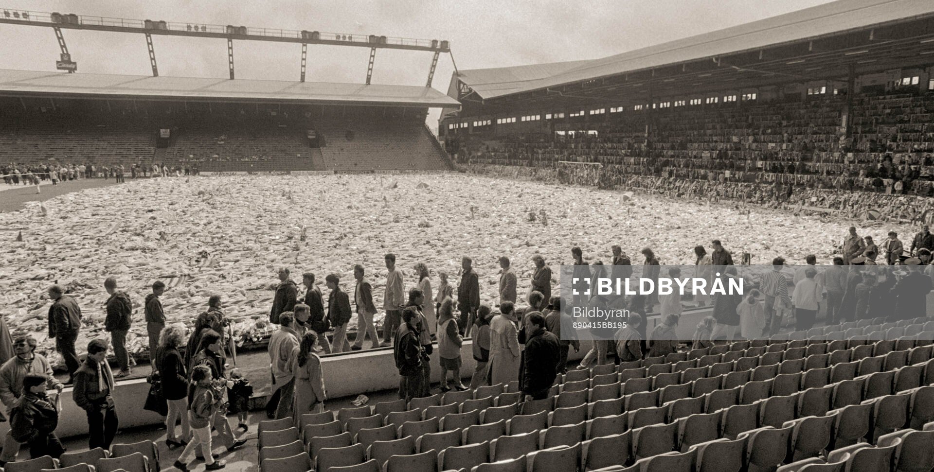 People look at a sea of flowers and scarves at Anfield to
