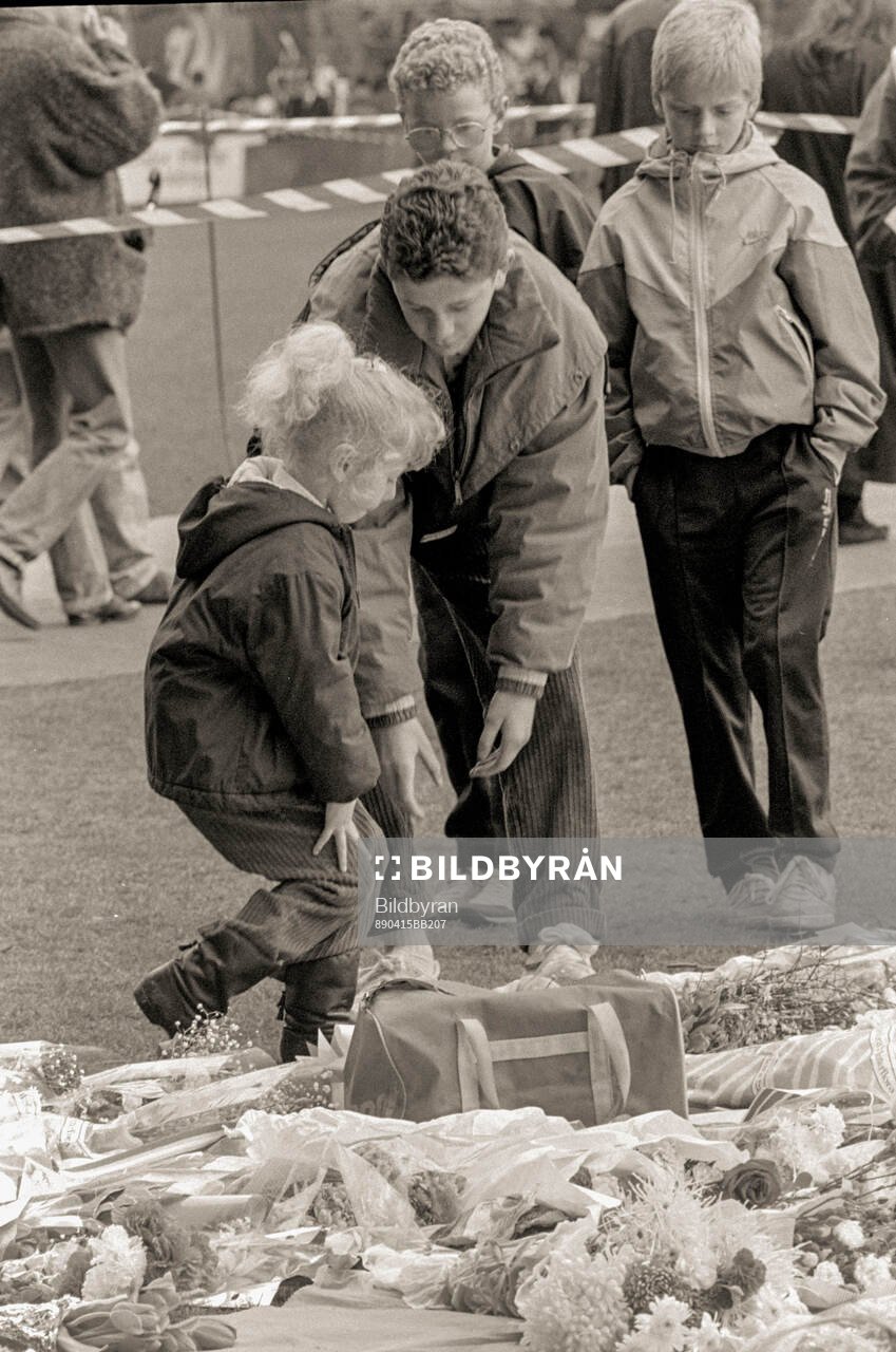 People lay flowers and scarves at Anfield to pay tribute to