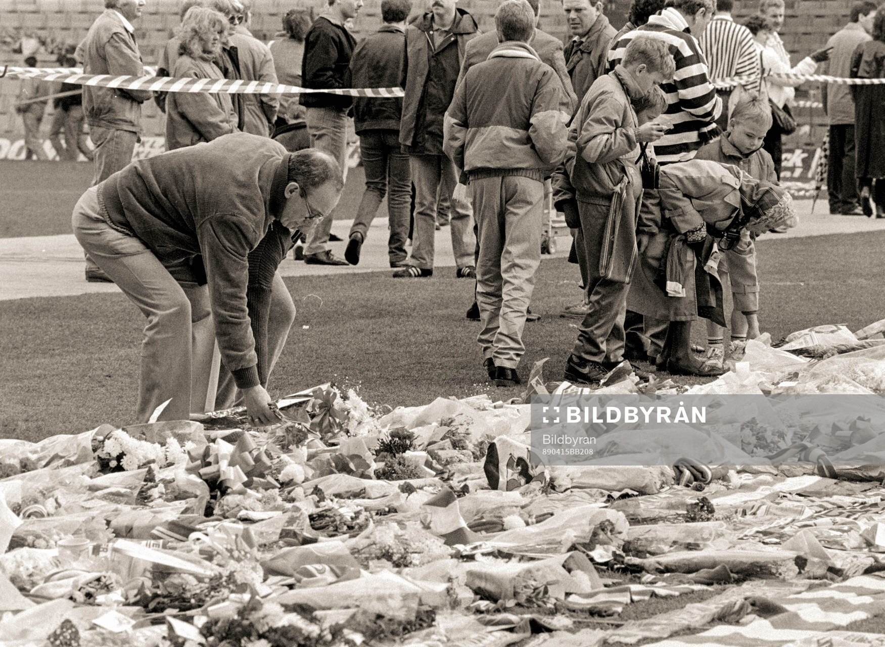 People lay flowers and scarves at Anfield to pay tribute to