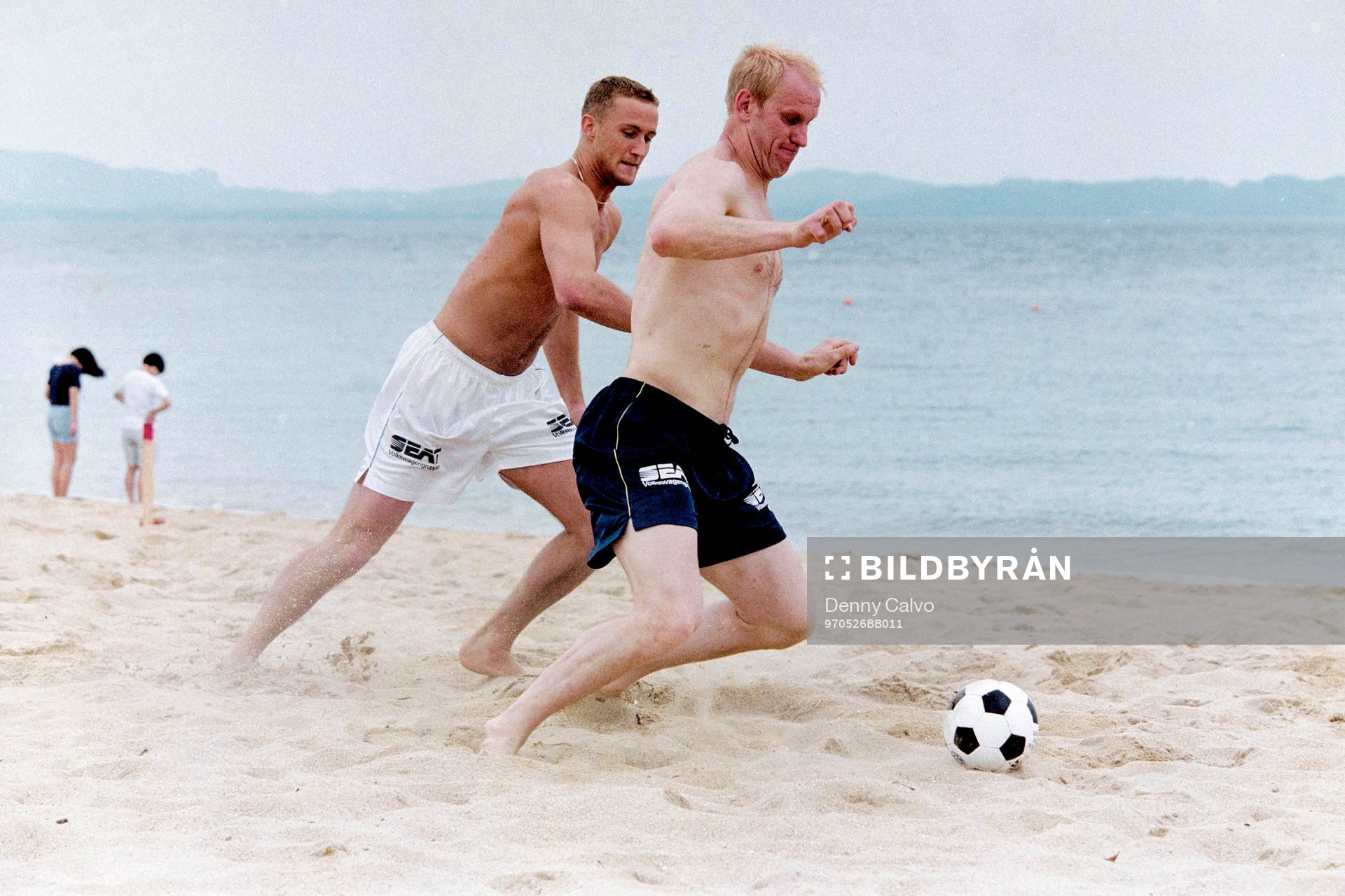 Andreas Larsson och Mats Olsson spelar fotboll på stranden