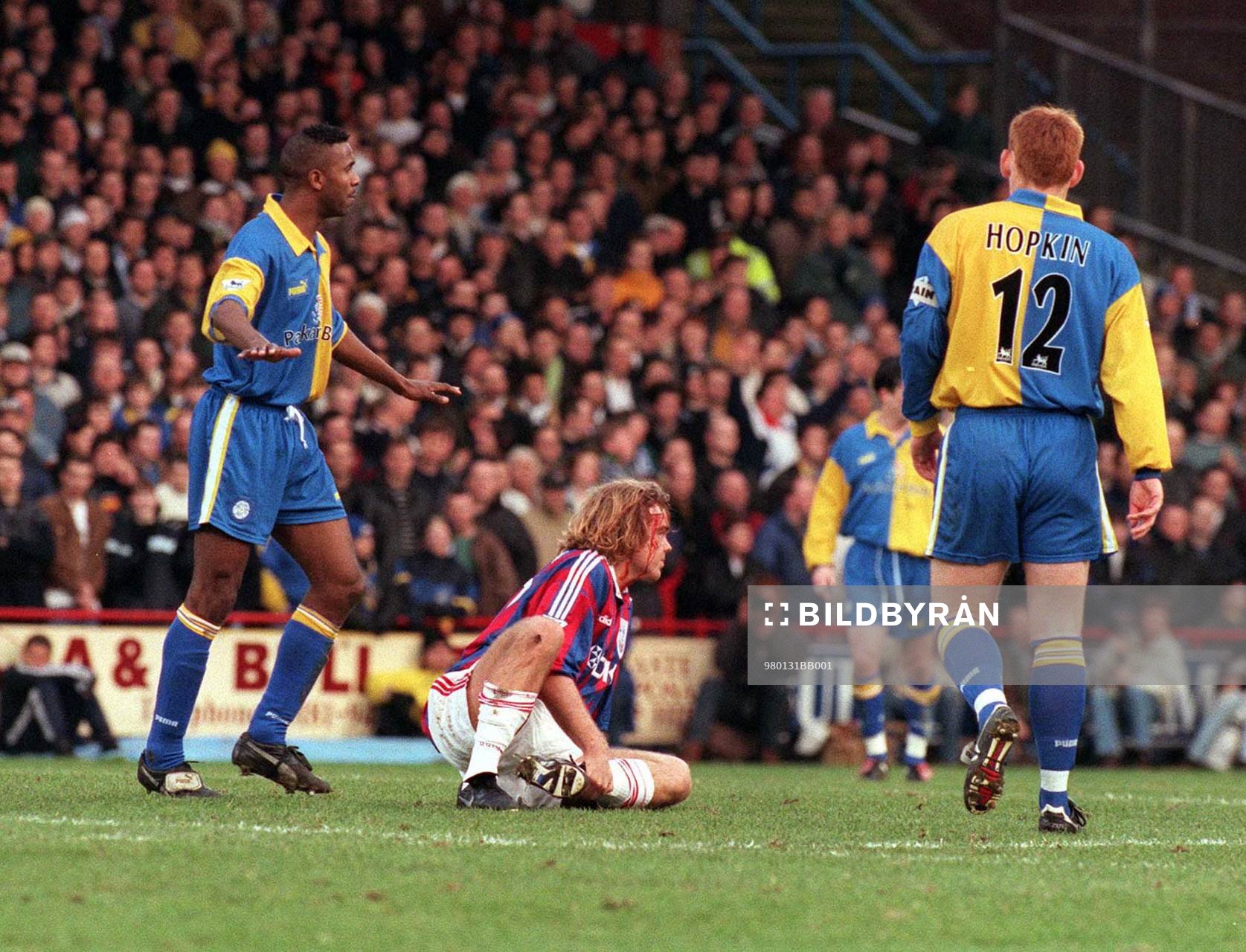 En blodig Tomas Brolin mellan Lucas Radebe och David Hopkin