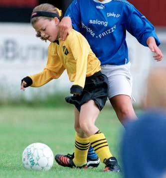 En flicka som försöker täcka bollen för en betydligt