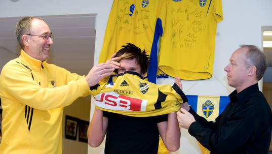  André Bengtsson, 16 år, IFK Hässleholm: Affe Jönsson, tränare, och Michael Engel, värvningsansvarig, hjälper André att ta på IFK-tröjan.