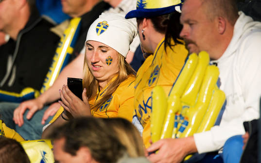 Svensk supporter fingrar med mobilen, mobiltelefon
