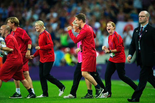  USA:s ledare, däribland Tony Gustavsson och Pia Sundhage, går in mot plan jublandes. Jubel.