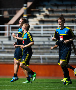 Pontus Wernbloom (v) och Sebastian Larsson (m) skrattar när de värmer upp på Sveriges träning 6 juni 2013 i Stockholm. Till höger är Rasmus Elm.