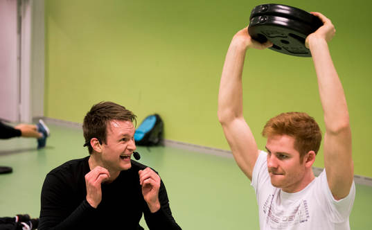 En instruktör peppar en ung man som tränar med vikter