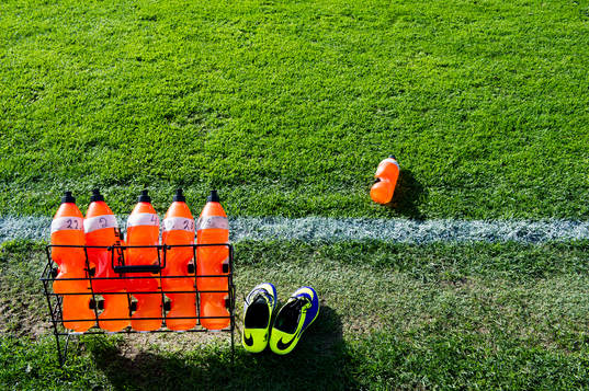 Ett ställ med vattenflaskor och ett par fotbollsskor