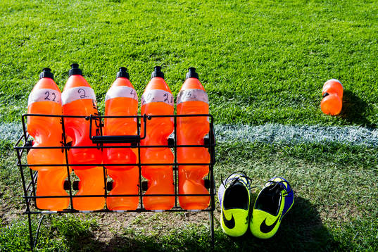 Ett ställ med vattenflaskor och ett par fotbollsskor