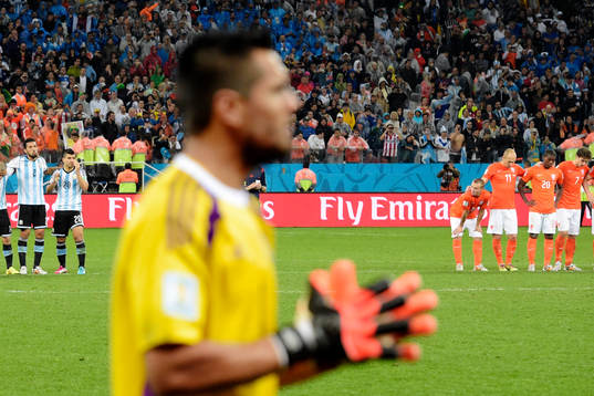 Hollands spelare ser på när Argentinas målvakt Sergio Romero (i förgrunden) gör sig redo för straffar