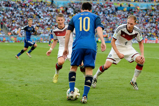 Tysklands Bastian Schweinsteiger och Benedikt Hoewedes markerar Argentinas Lionel Messi