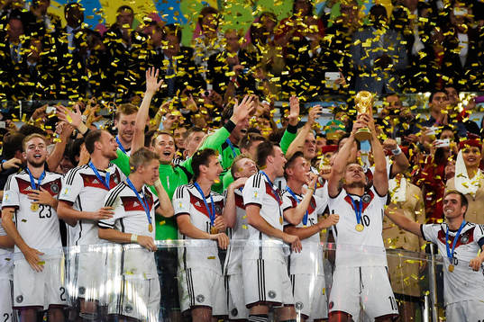Tysklands spelare jublar när Lukas Podolski lyfter pokalen efter finalen mellan Argentina och Tyskland