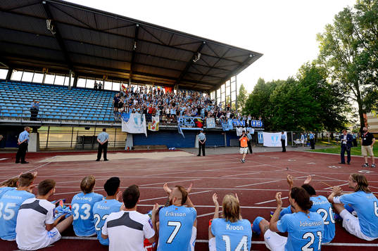 Malmö FFs spelare sätter sig framför klacken som sjunger 