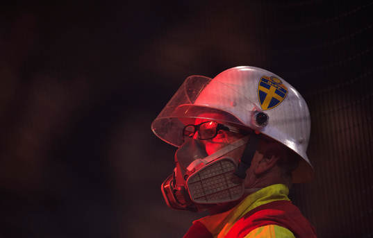 En funktionär har på sig gasmask när AIK-fans eldar
