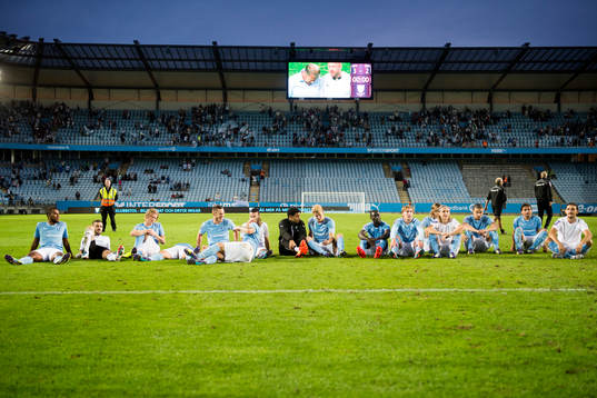 Malmö FFs spelare sitter på planen och lyssnar på klacken sjunga