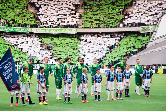 Hammarbys spelare står uppställda framför supportrarnas tifo