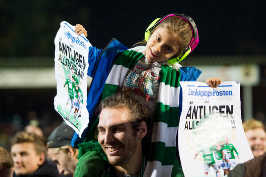 En ung supporter med hörselkåpor och löpsedlar med
