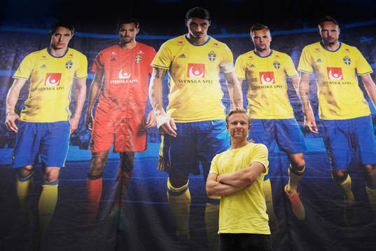Bildbyråns fotograf Joel Marklund poserar framför en bild - som är tagen av honom - med porträtt på Kim Källström, Andreas Isaksson, Zlatan Ibrahimovic, Sebastian Larsson och Andreas Granqvist i presscentret