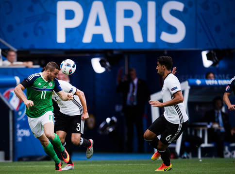 Nordirlands Conor Washington nickar mot Tysklands Sami Khedira i fotbollsmatchen mellan Nordirland och Tyskland