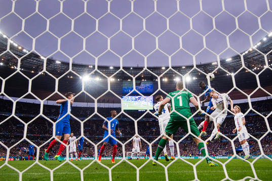 Frankrikes Paul Pogba nickar in 2-0 i en duell med Islands Jón Dadi Bödvarsson bakom Islands målvakt Hannes Halldorsson och Birkir Saevarsson