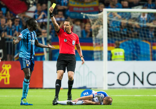 Domare Martin Strömbergsson delar ut ett gult kort och