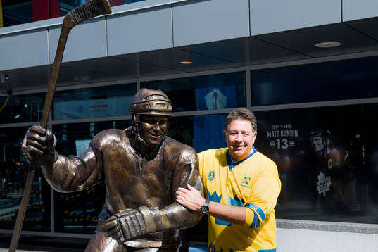 En svensk supporter blir fotograferad framför en staty av