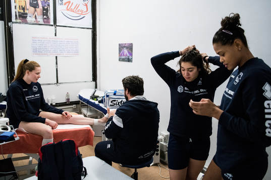 Volleybollspelaren Isabelle Haak får behandling av klubbens sjukgymnast Marco Zenato och bredvid står lagkompisarna Martina Ferrara och Adenízia da Silva