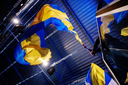 En HV71-supporter vevar med en blågul flagga