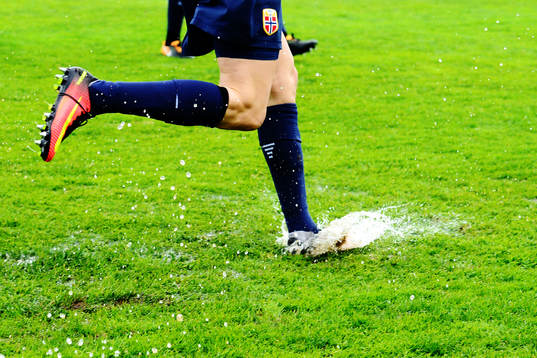 Norges spelare springer på en blöt fotbollsplan