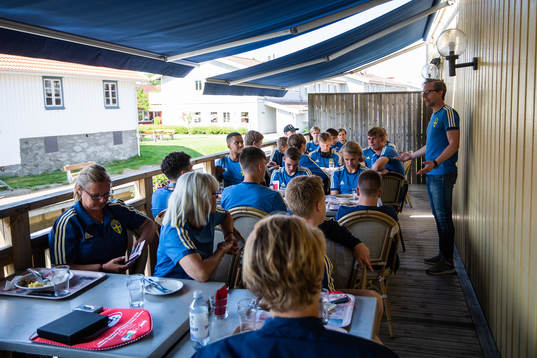Sveriges förbundskapten Christofer Augustsson pratar framför spelarna på restaurang
