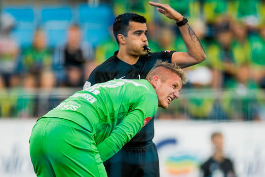 Goalkeeper Eirik Holmen Johansen of Sandefjord reacts to an injury next to Rohit Saggi, referee, during the Eliteserien match between Sandefjord and Tromsø on August 10, 2018 in Sandefjord.
