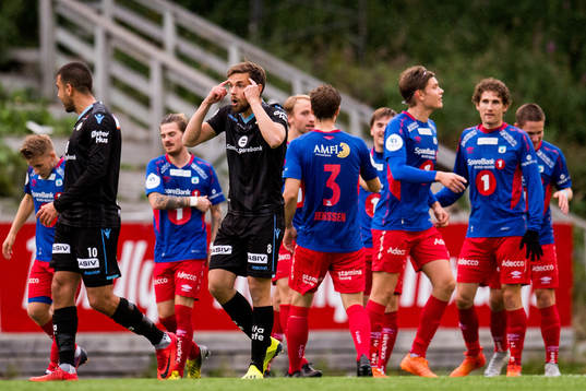Remi Johansen of Sandnes Ulf reacts while the players of Tromsdalen celebrate the 2-0 goal