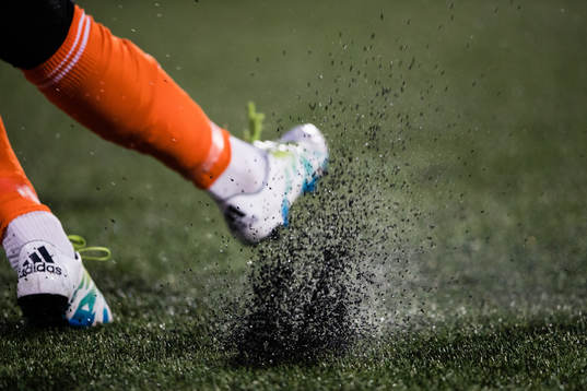 Granulat sprutar när en spelare skjuter iväg bollen