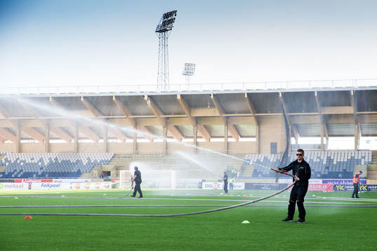 Funktionärer vattnar planen för hand på Studenternas IP