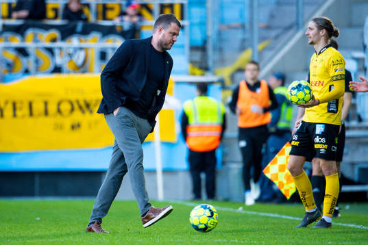 Elfsborgs tränare Jimmy Thelin hämtar en boll på planen framför Pawel Cibicki