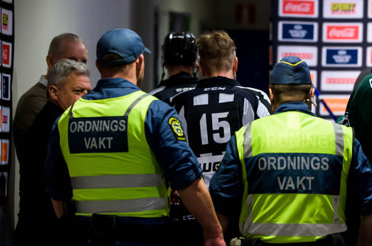 Domare Patrik Sjöberg blir eskorterad av vakter in till