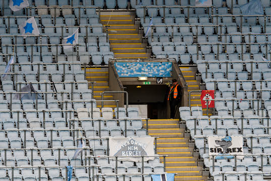 En ensam publikvärd på en tom läktare med flaggor