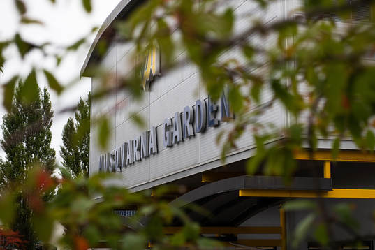 Skylt på Husqvarna Garden med träd i förgrunden