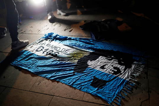  An Argentine flag with the face of late Argentine soccer legend Diego Armando Maradona painted on it is seen on the floor during a tribute to him the day after his death, in Barcelona, Spain, November 26, 2020.  REUTERS/Nacho Doce 