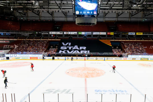 Pappfigurer och Banderoll med Texten ”Vi står kvar”