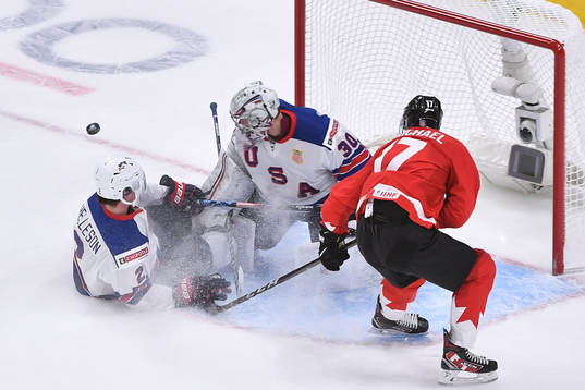 Drew Helleson of USA slides into his netminder Spencer