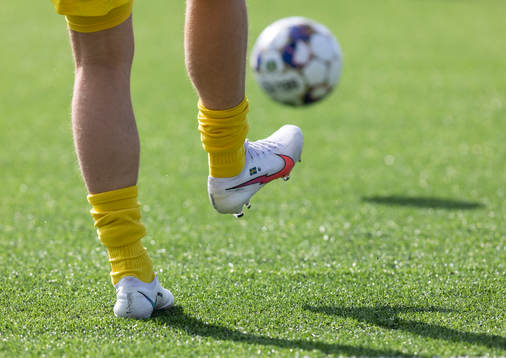 En fot med fotbollssko och en boll