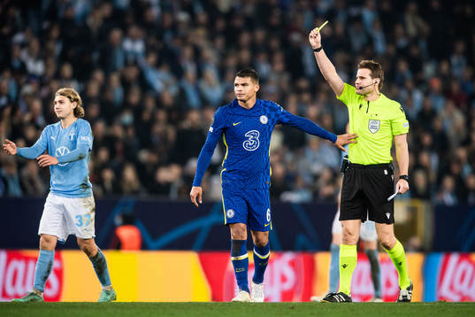 Referee Felix Brych shows Thiago Silva of Chelsea a yellow card