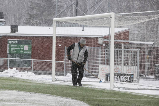 Funktionär sopar planen innan fotbollsmatchen i Superettan