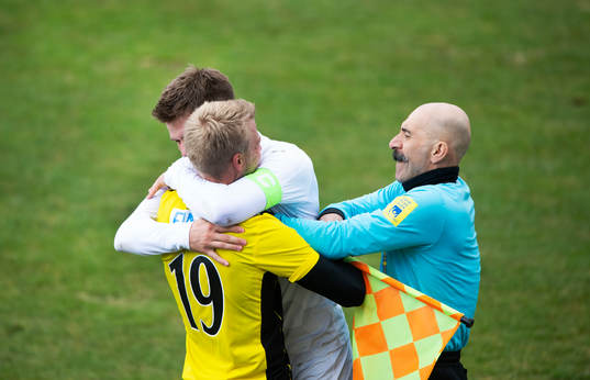 En Rosengårds-spelare kramar spontant om IFK Hässleholms Jens Lynard medan assisterande domaren försöker avvärja kramen i matchen i div. 2 Södra Götaland mellan IFK Hässleholm och FC Rosengård i Hässleholm 15 april 2022.
