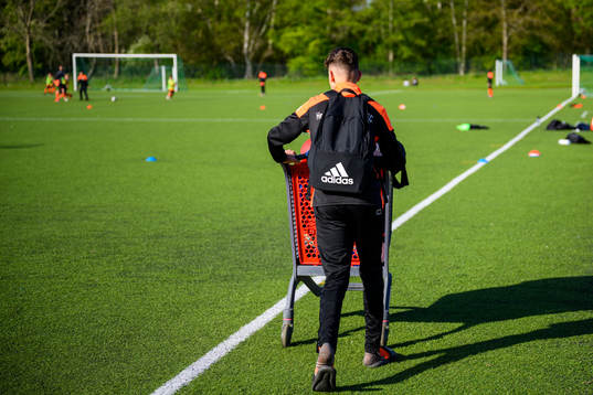 En av de äldre spelarna bär ut material i en kundvagn