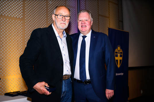 Carl Gustav Larsson tar emot ett förtjänsttecken i guld