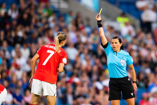 Carina Wenninger of Austria is shown a yellow card by referee Kateryna Monzul