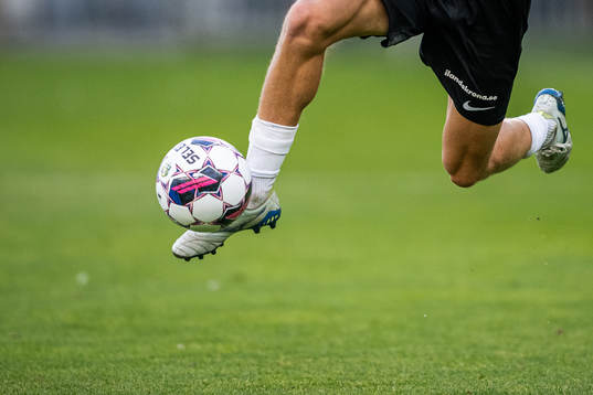 En fotbollsspelare springer med bollen